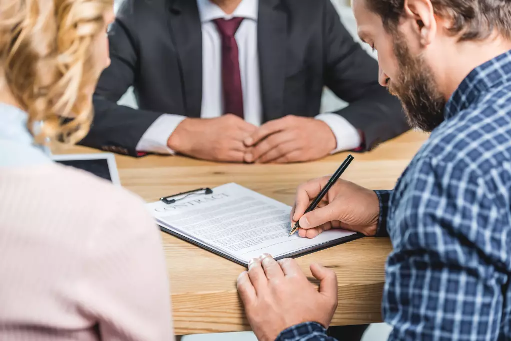 Selective focus of man signing contract at table in lawyer's office