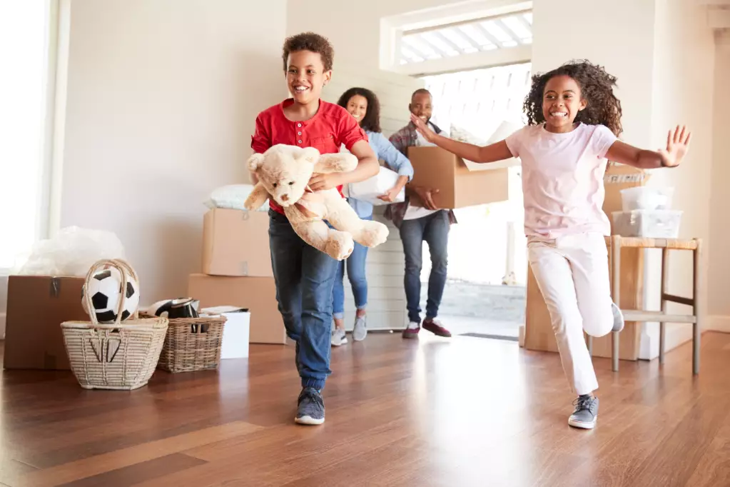 Excited Family Carrying Boxes Into New Home On Moving Day