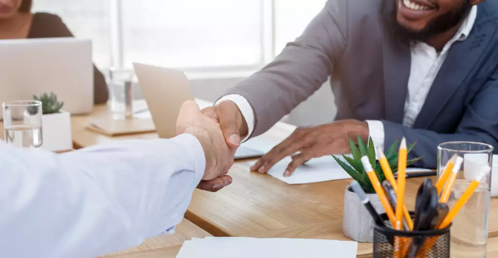 Business men shaking hands after signing deal at meeting in office